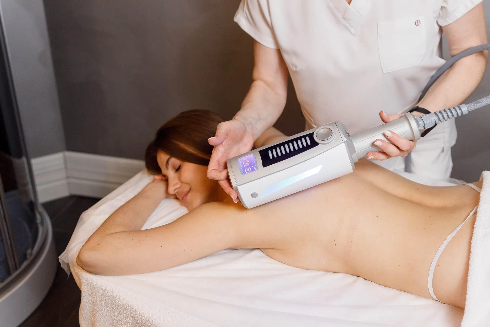 A practitioner working across a client's back with the roller-matrix handpiece